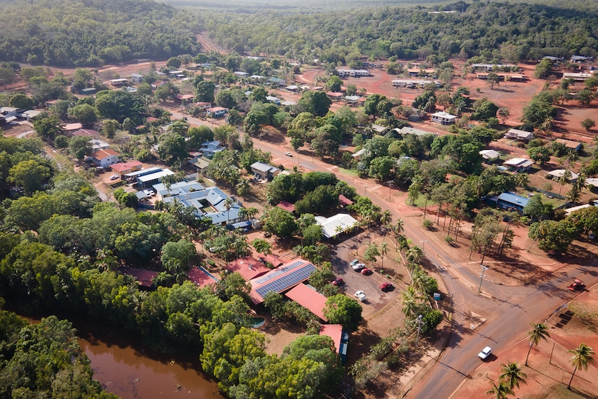 An aerial image of a remote town, with lots of greenery and red dirt.