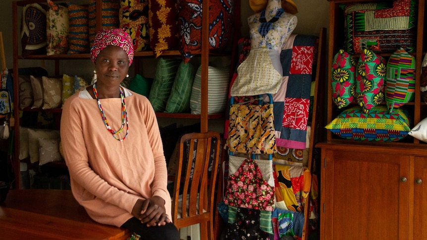 A woman sits in front of brightly coloured cushions and homewares