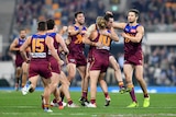 AFL teammates run to the player who has just kicked a vital goal.