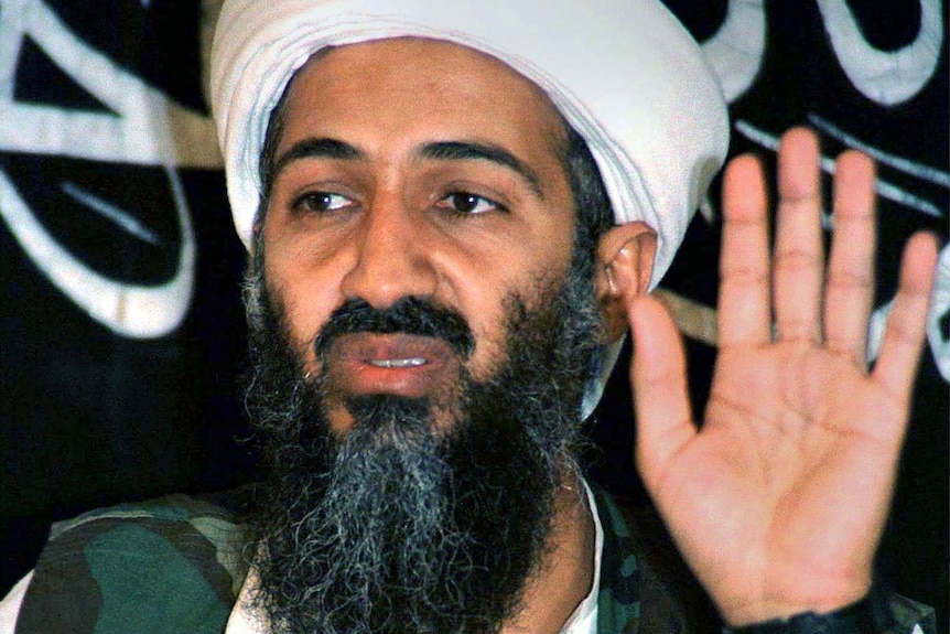 Osama bin Laden with his hand raised.