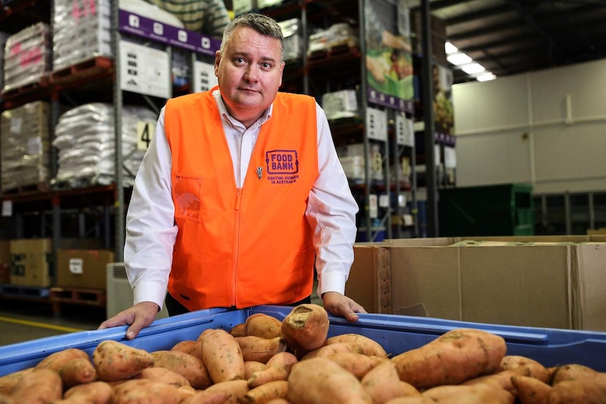 Foodbank Queensland CEO Michael Rose stands with a tray of food at a warehouse in Brisbane