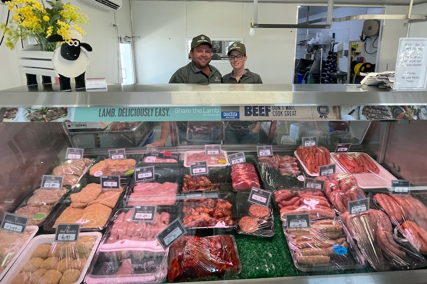 Man and woman stand behind butcher meat display