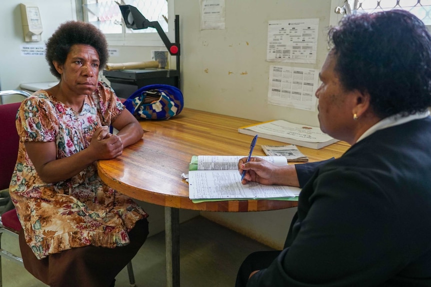 A woman talking to a nurse at a desk