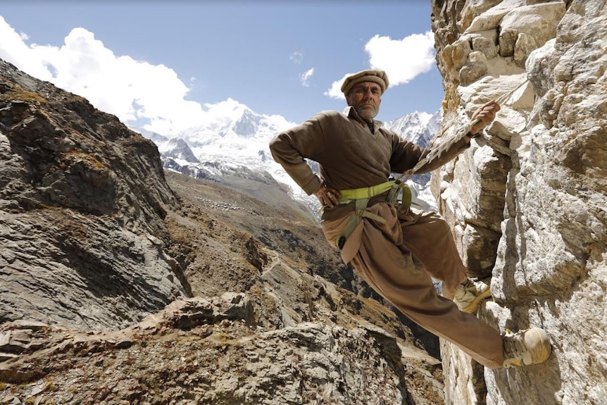 Muhammed poses while standing on the edge of a mountain in Northern Pakistan