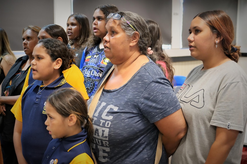 A group of older women and children sing together.