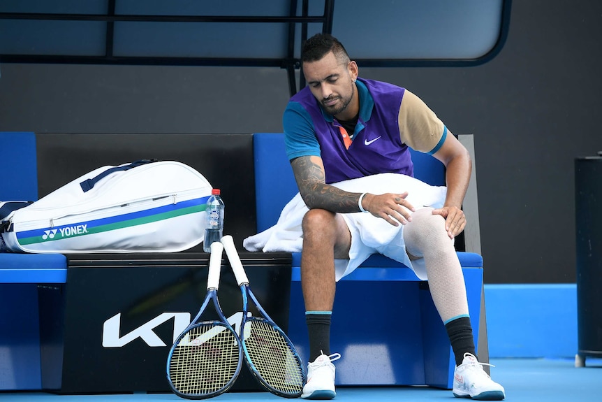 Nick Kyrgios holds his left knee and grimaces