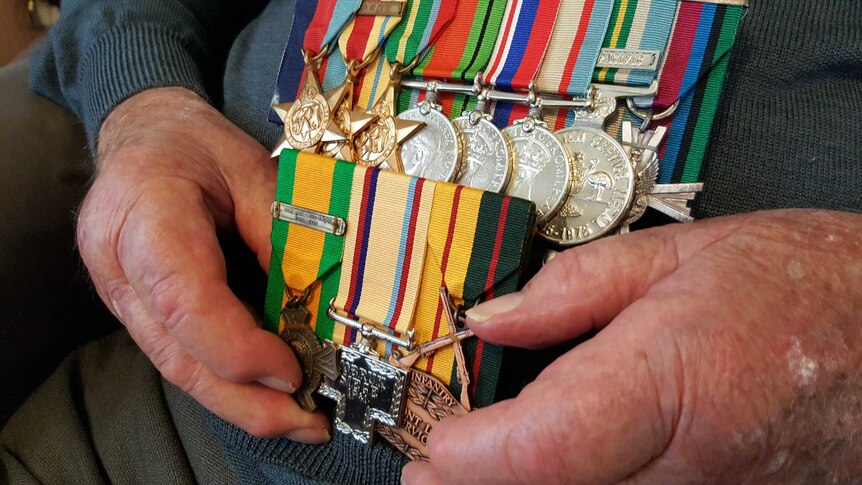 Harry Lock holds his war medals from WW2.