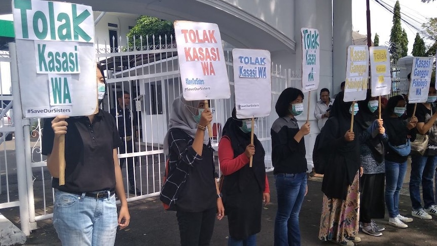 Women wearing masks holding signs in Indonesian which translates to "reject the appeal of WA".