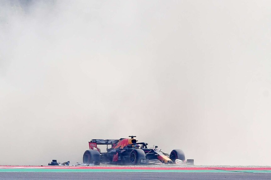 Max Verstappen's Red Bull in a cloud of dust.