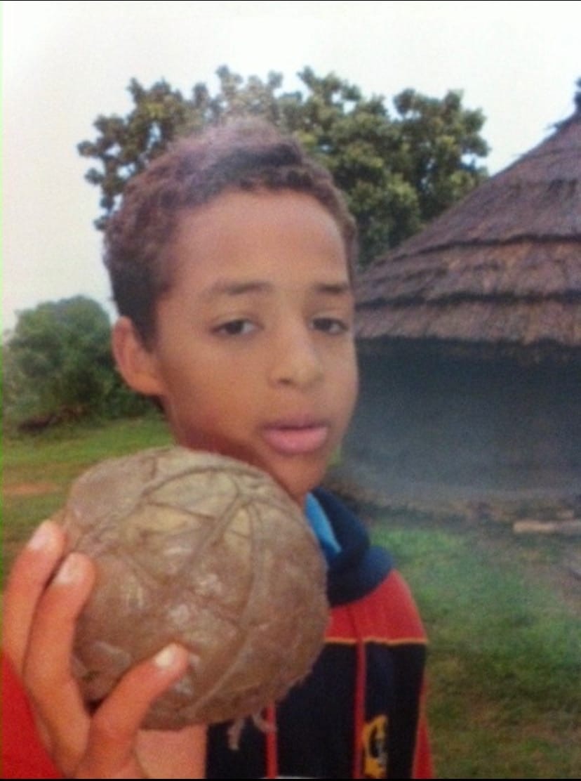 Um menino segura uma bola feita de sacos plásticos enrolados e barbante