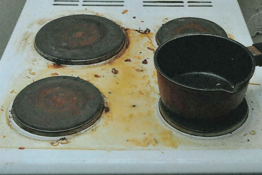 A close up of a dirty stove top streaked with dirt and food. 