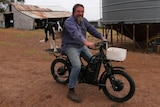 a man and his dog sit on an UBCO electric motorcycle