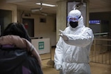 Worker in hazardous materials suit stops a passenger in the Beijing subway.