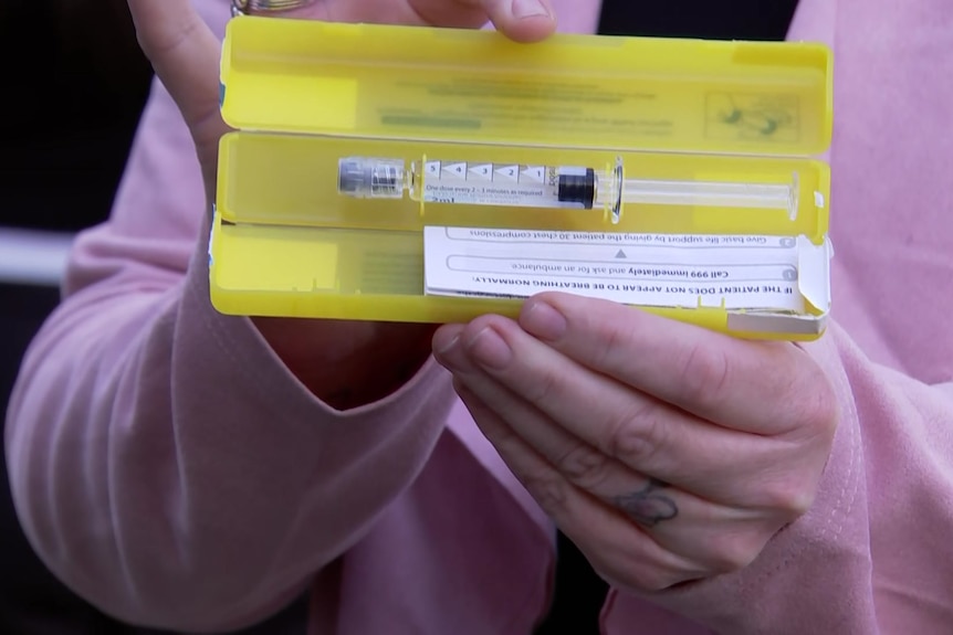 hands hold a pre-loaded syringe in a yellow casing.