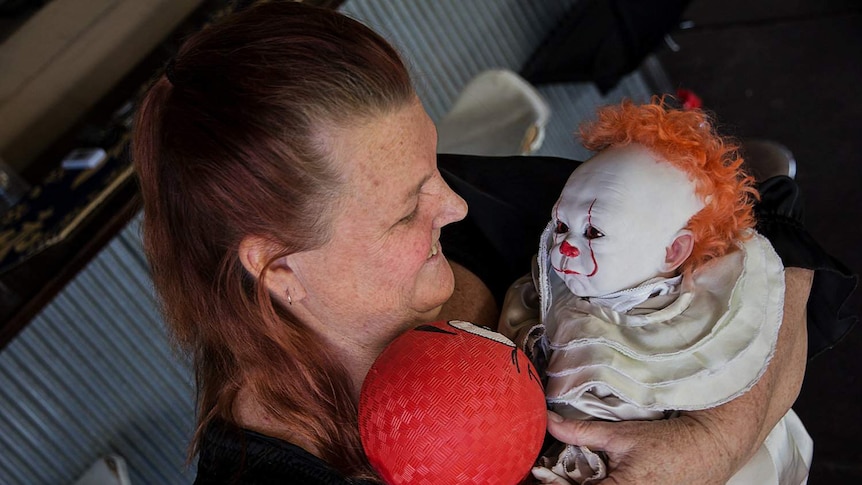A woman holds a lifelike clown baby doll