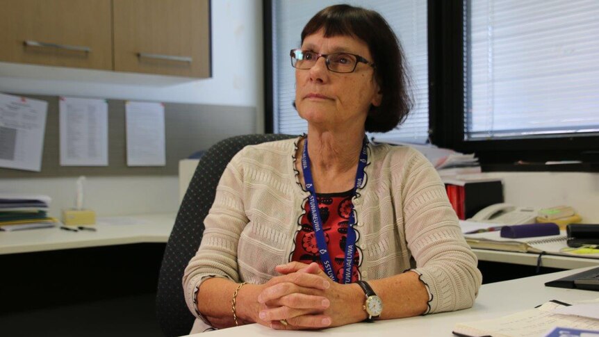 State School Teachers' Union of WA president Pat Byrne sits at her desk in an office with her arms clasped in front of her.