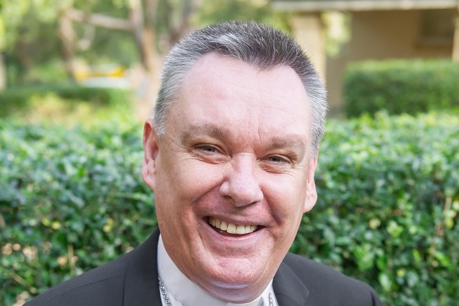 A medium close up portrait of Bishop Tim Harris smiling outdoors.