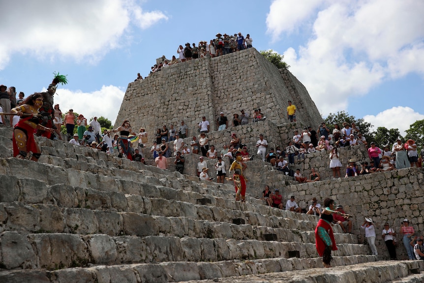 People standing on the steps and platforms of the Edzna archeological site