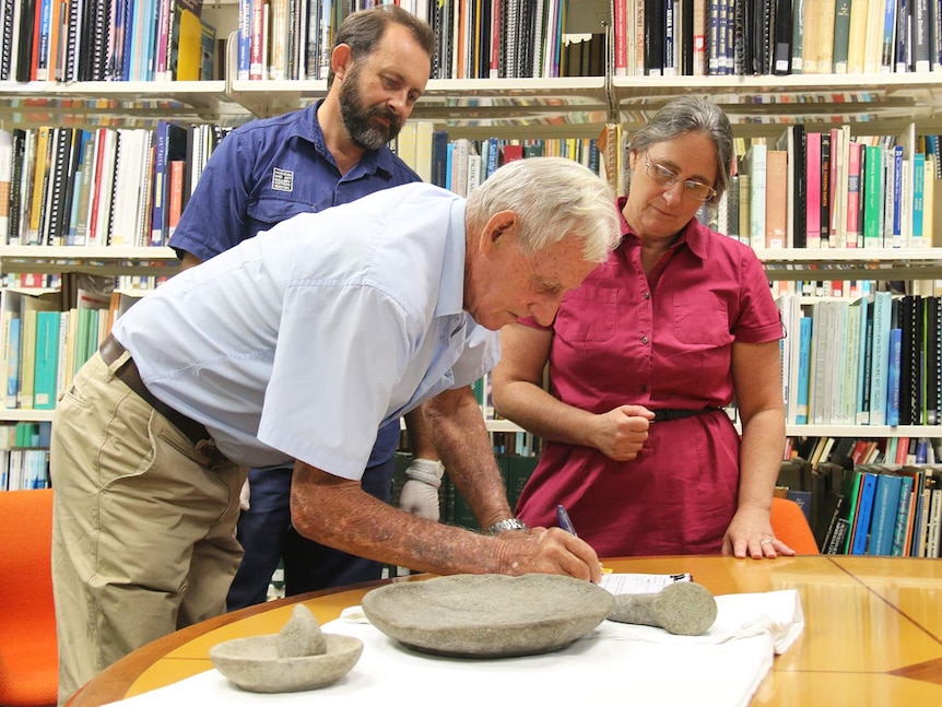 John McQueen shows the items to staff from the MAGNT.