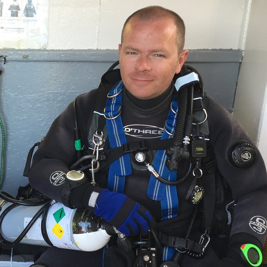 A fair-haired, balding man decked out in scuba gear.