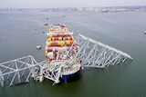 a view of a cargo ship destroyed from the front with collapsed metal beams of a bridge on top
