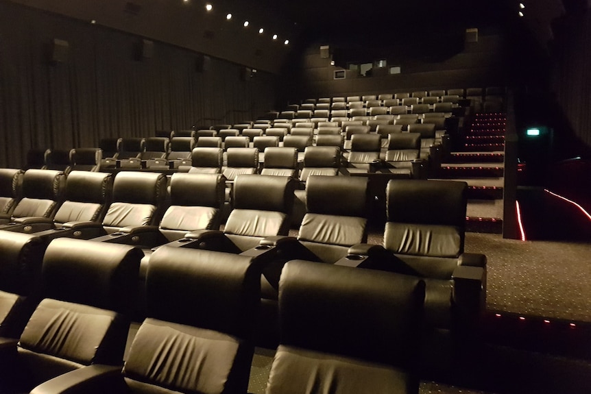 An entirely empty cinema filled with black leather chairs.