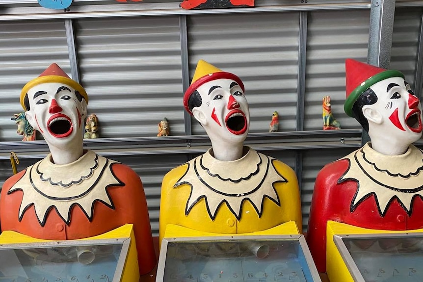 Three fairground clowns in a shed