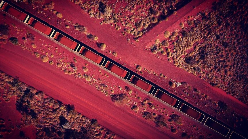 An aerial photo of an iron ore train surrounded by the red dirt of the Pilbara in Western Australia