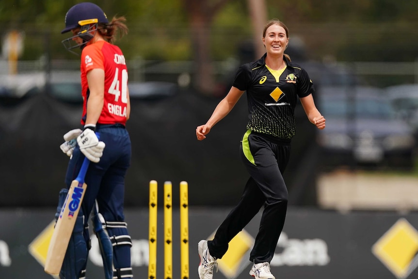 A smiling female fast bowler celebrates a clean-bowled ODI wicket as the batter walks off.