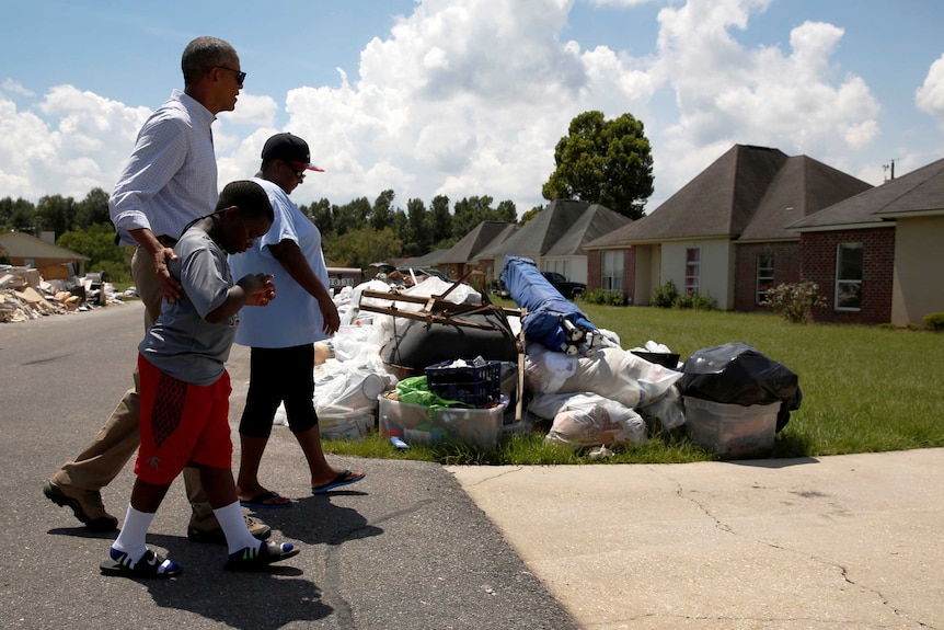 Barack Obama walks with a family in Louisiana after flooding in the state.