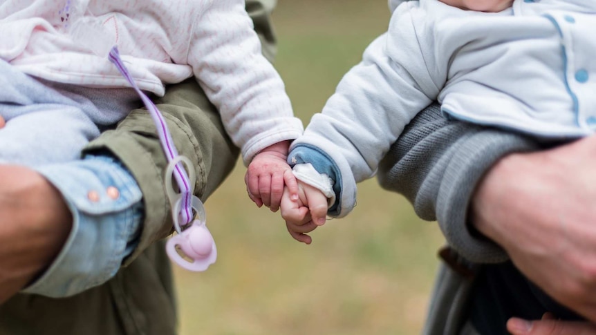 two babies hold hands