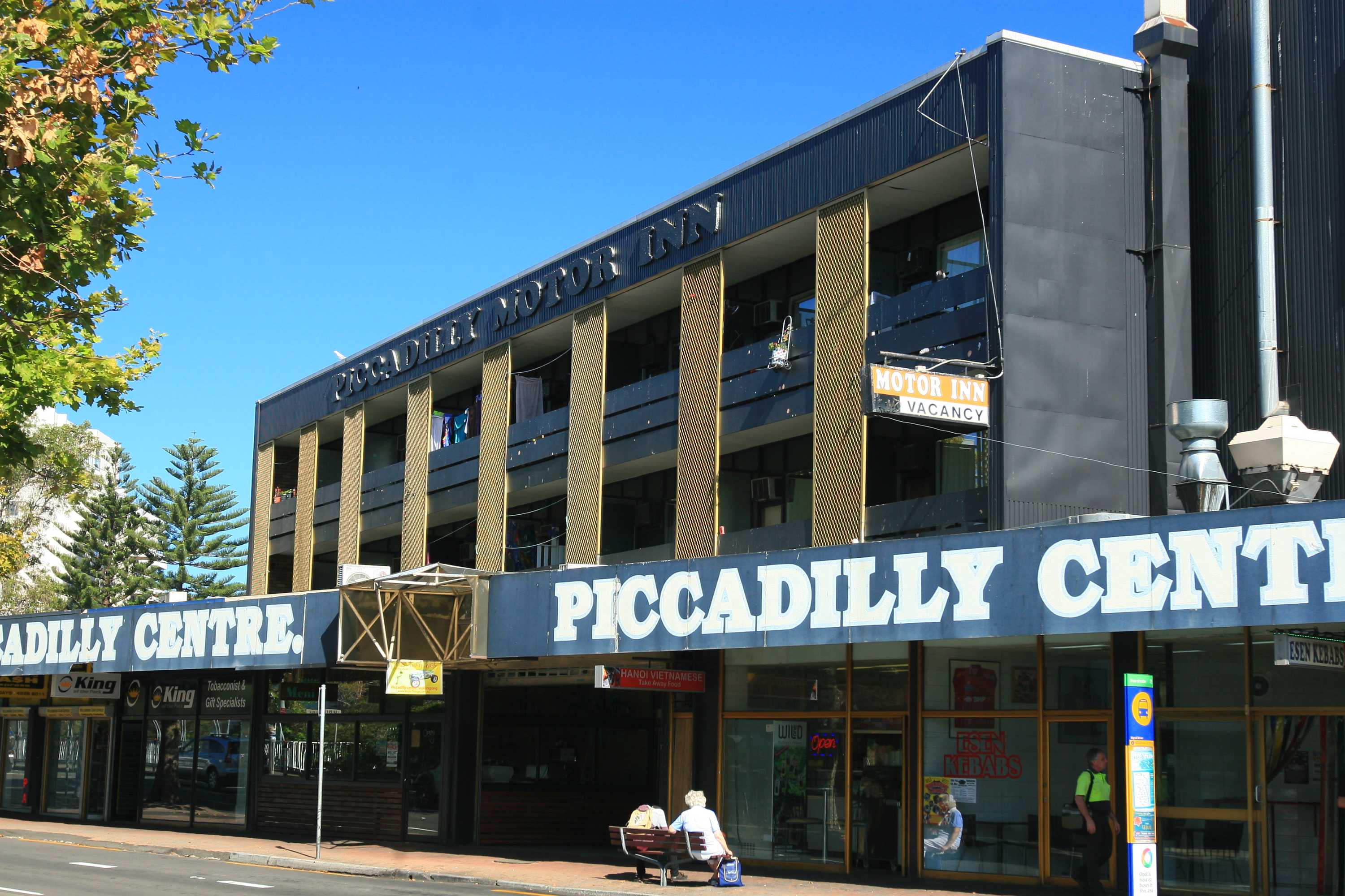 A low high-rise building that says "Piccadilly Centre", with a smaller sign saying "Motor Inn".