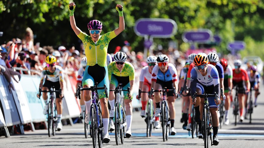 An Australian cyclist raises her arms in triumph as she crosses the finish line in The Commonwealth Games women's road race.