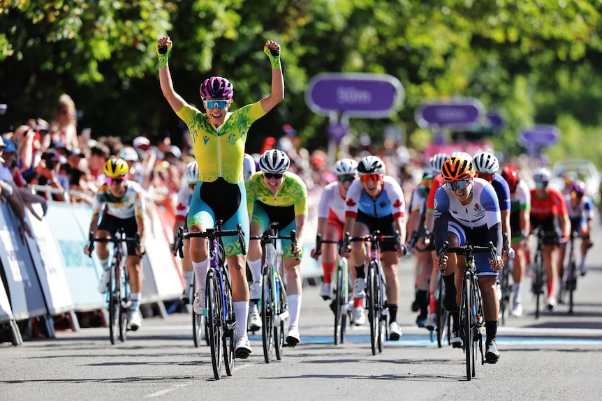 An Australian cyclist raises her arms in triumph as she crosses the finish line in The Commonwealth Games women's road race.
