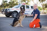 Gemma Wood shakes hands with SES search dog Jagger in front of SES vehicle
