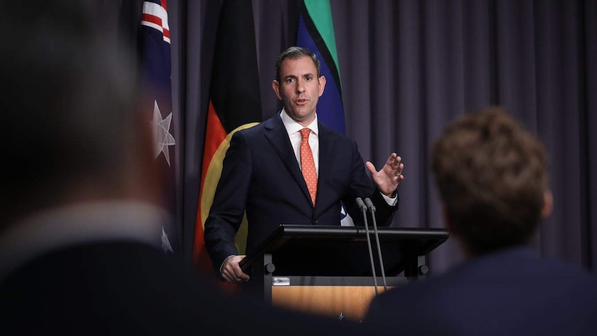 A man in a suit and tie speaks to seated media in Parliament House's Blue Room.