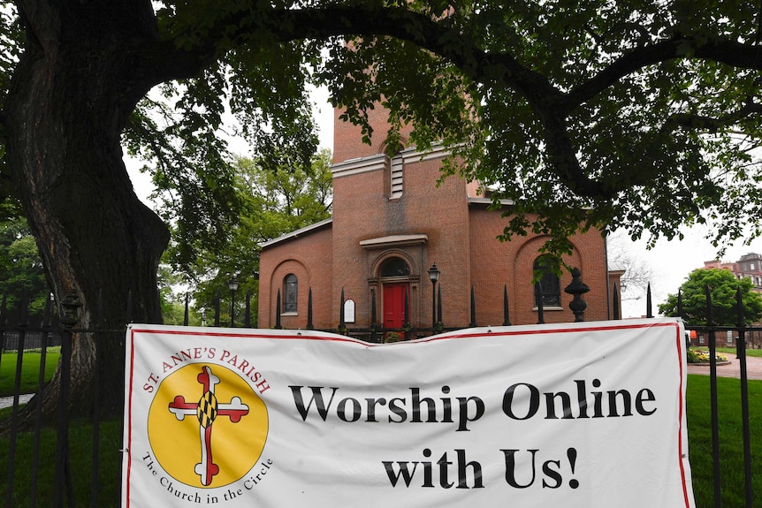 A sign hangs on the fence of a church