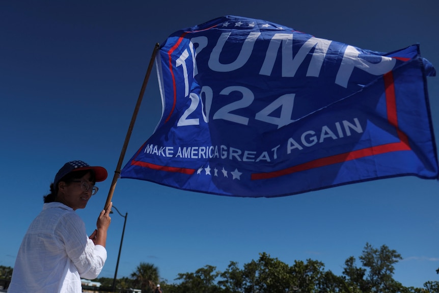 A woman holds a Trump flag.