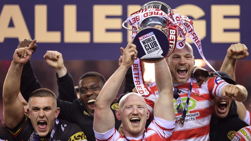Wigan players hold up the World Club Challenge trophy as they celebrate beating Penrith.