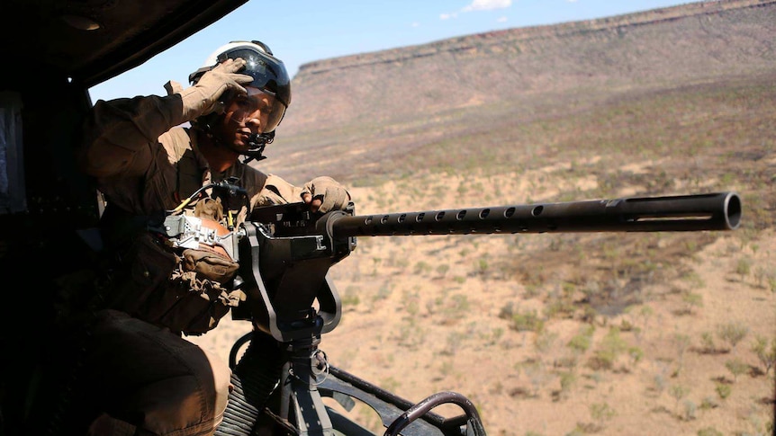 A US Marine looks out the side of a UH-1Y Huey helicopter