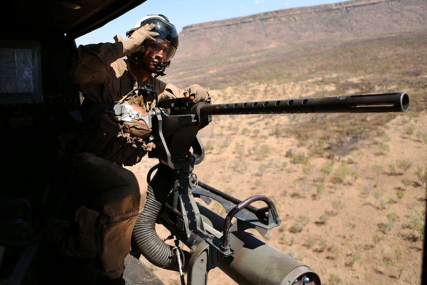 A US Marine looks out the side of a UH-1Y Huey helicopter