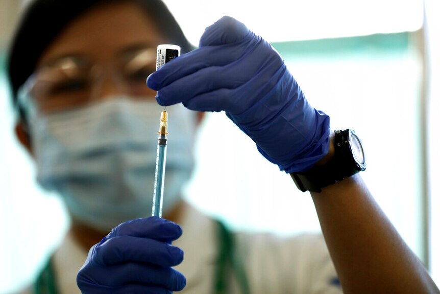 A medical worker fills a syringe with a dose of the Pfizer-BioNTech COVID-19 vaccine