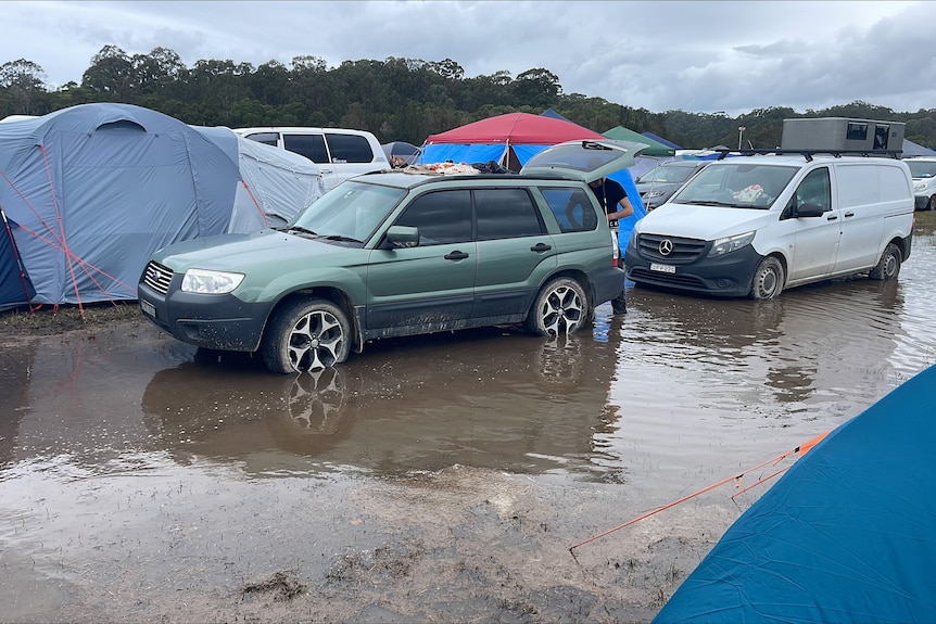 Cars in large puddles of water amid tents in the Splendour campground.