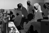 Black and white illustration of people in front of rows of computers, looking at screens.