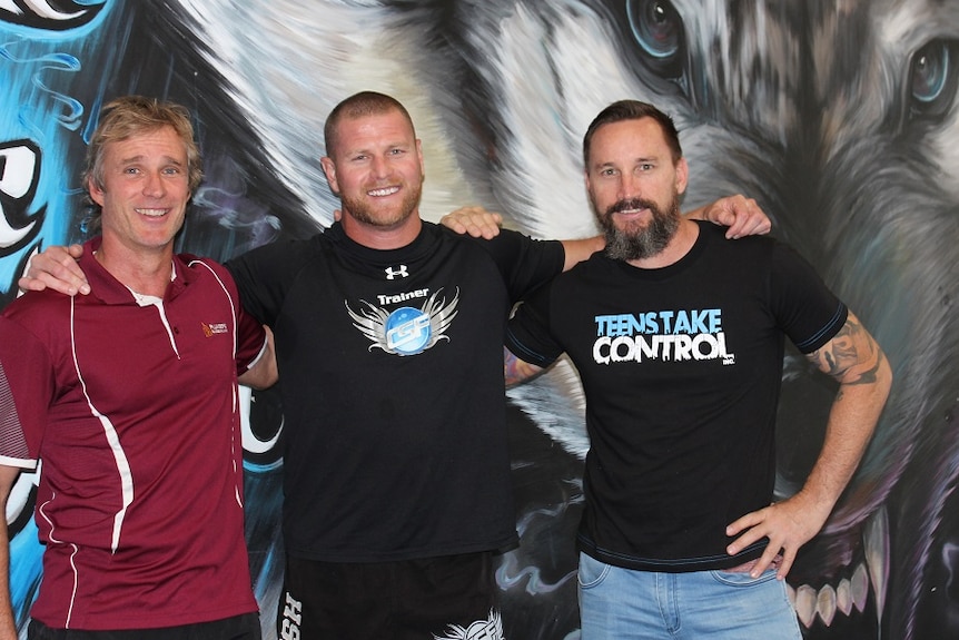 three men standing in a gym