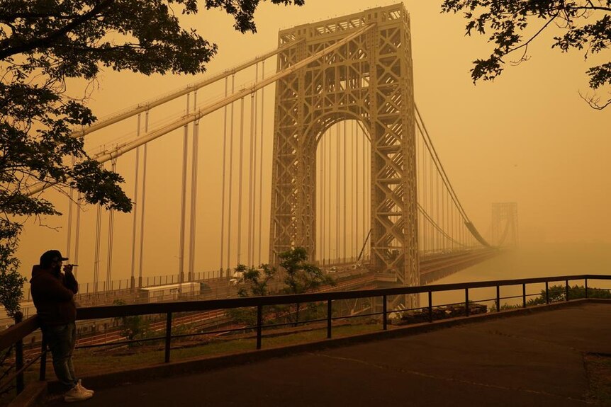 A man talks on his phone as he looks through the haze at the George Washington Bridge in Fort Lee. 