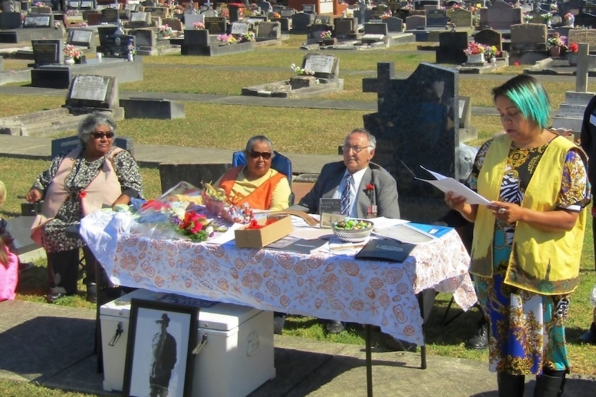A ceremony takes place at a cemetery.