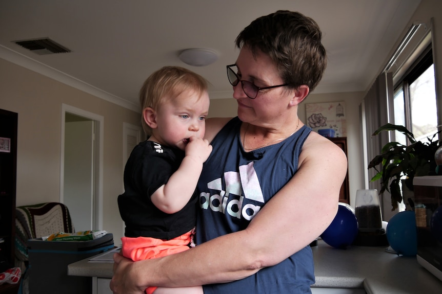 una mujer con cabello castaño corto sostiene a un bebé