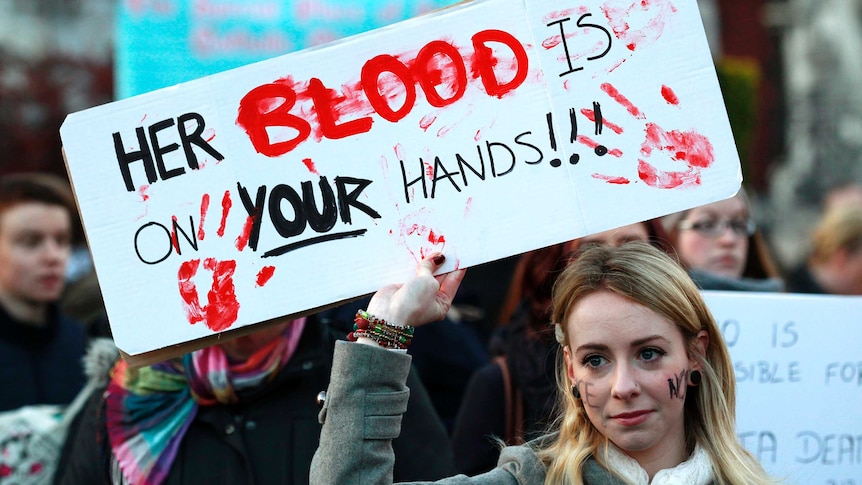 A woman holds a poster during a vigil in Dublin in support of changes to abortion law