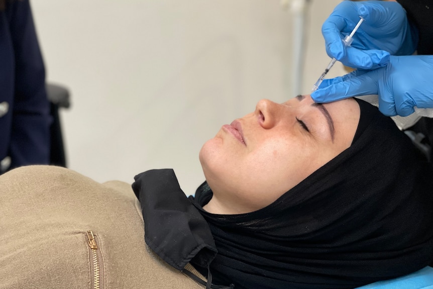 A woman having Botox injected into her eyebrow